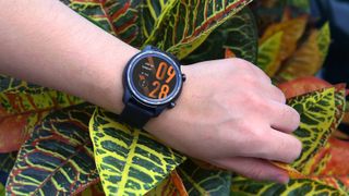 Die TicWatch Pro 3 Ultra Smartwatch an einem Handgelenk mit orangefarbener Beschriftung, die die Zeit anzeigt