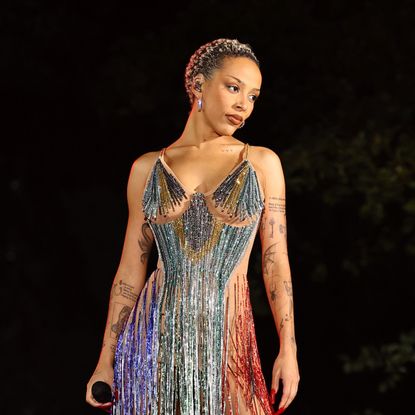 a woman with short hair standing on a stage wearing a short, sparkly dress with tassels