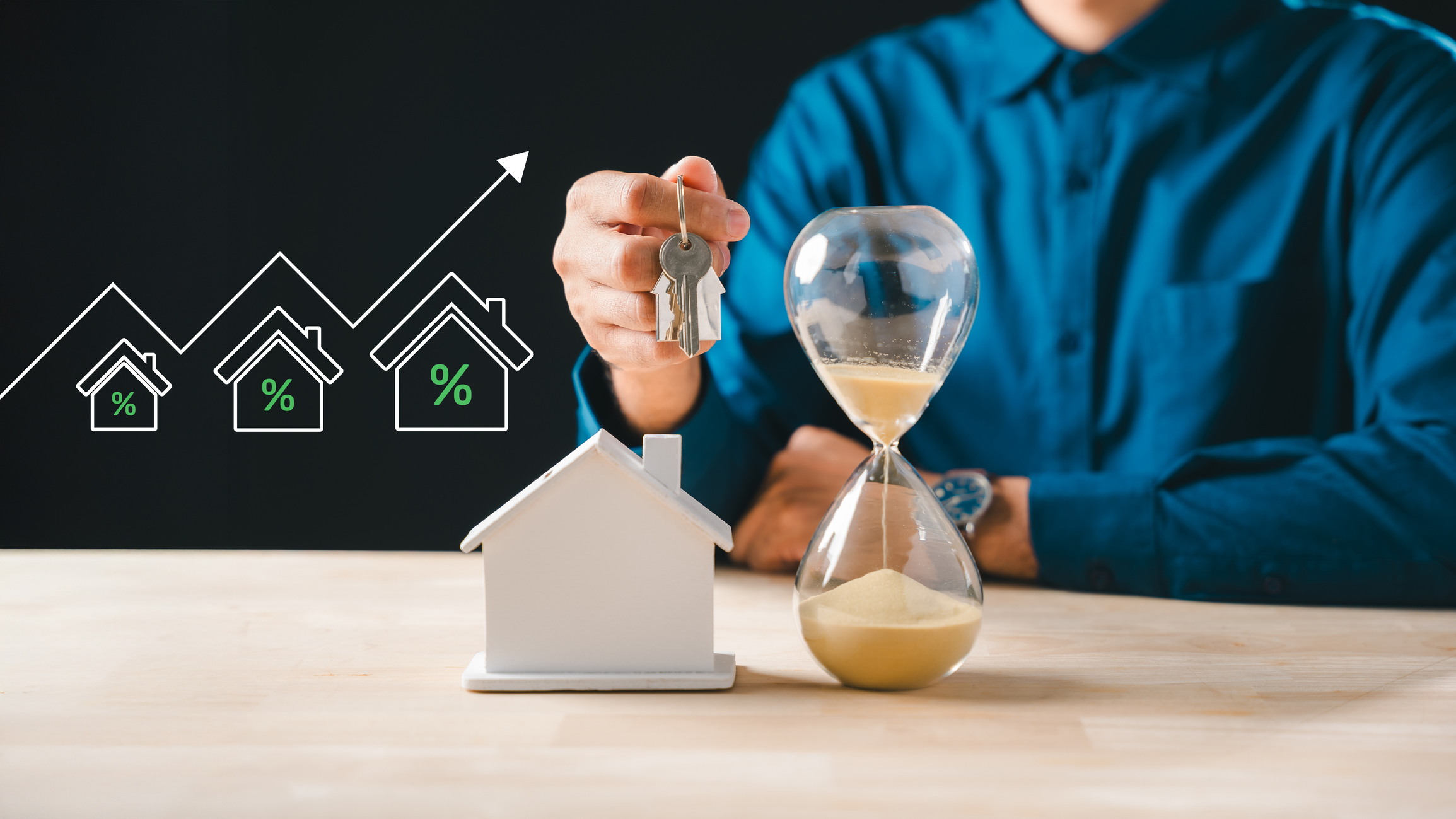 Person holds house keys, hourglass shows time for real estate property purchase
