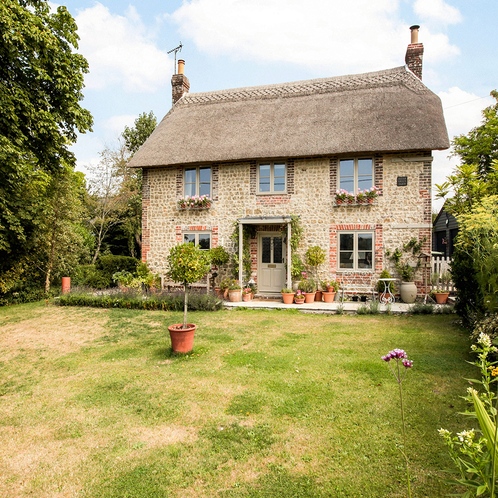 chocolate box cottage with brick walls and grass lawn