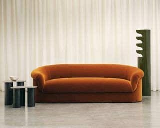 Sedilia orange modern curved sofa in front of large white curtain