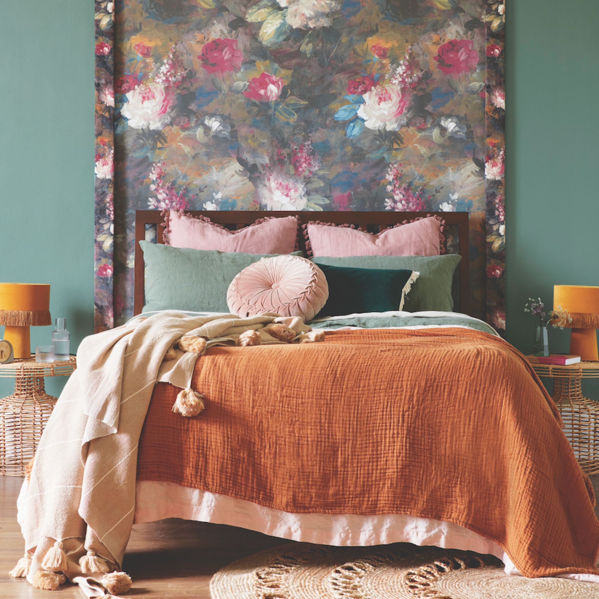 A bed with pink and orange bedding, framed with two orange table lamps on bedside tables