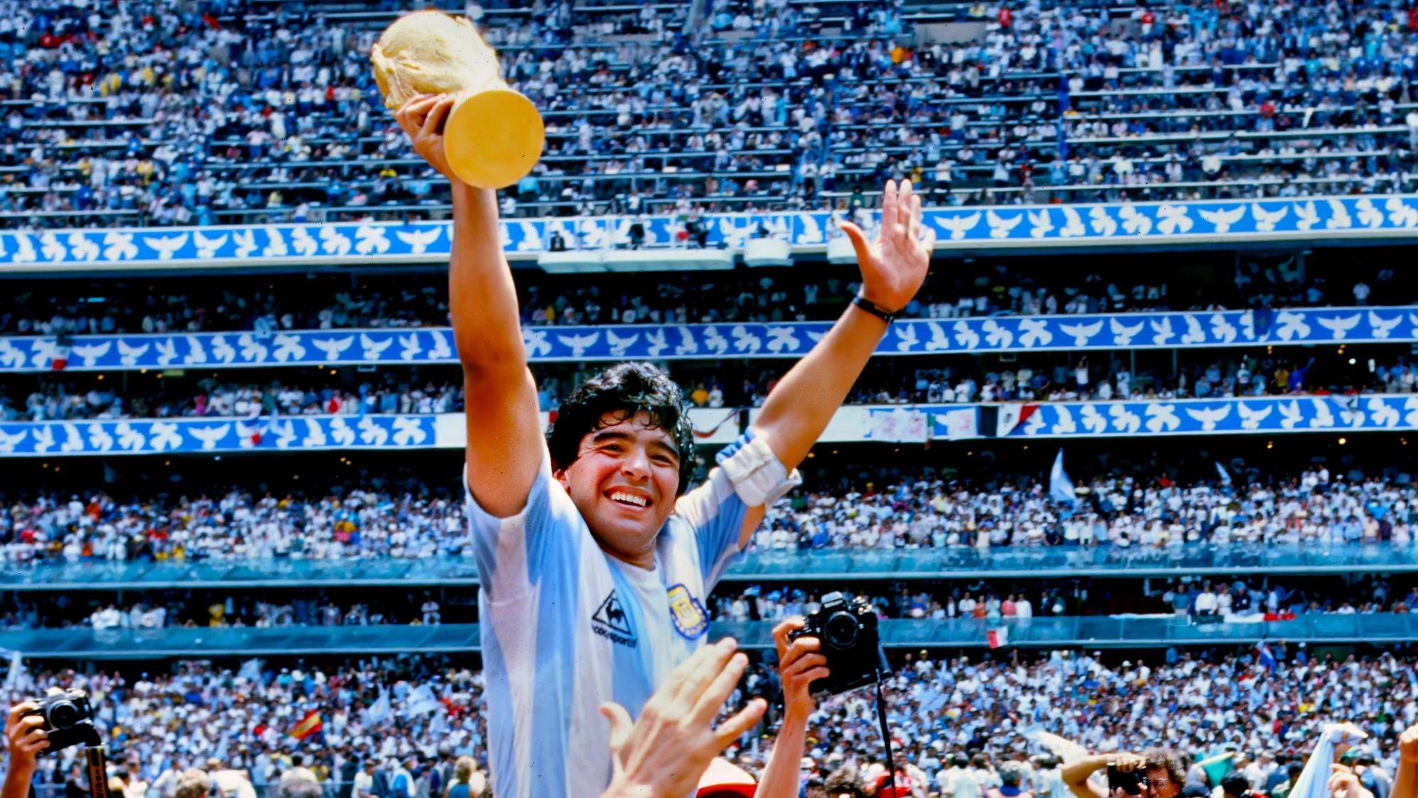 Diego Maradona hoists the FIFA World Cup trophy as he is carried off the field by fans and teammates after the 1986 FIFA World Cup Mexico Final between Argentina and West Germany on June 29th, 1986