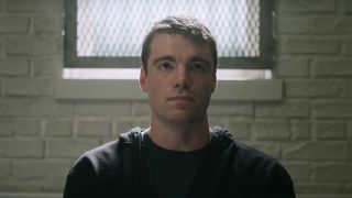 Gabriel Basso's character Peter Sutherland being held in a stark room with a brick wall and a gated window.