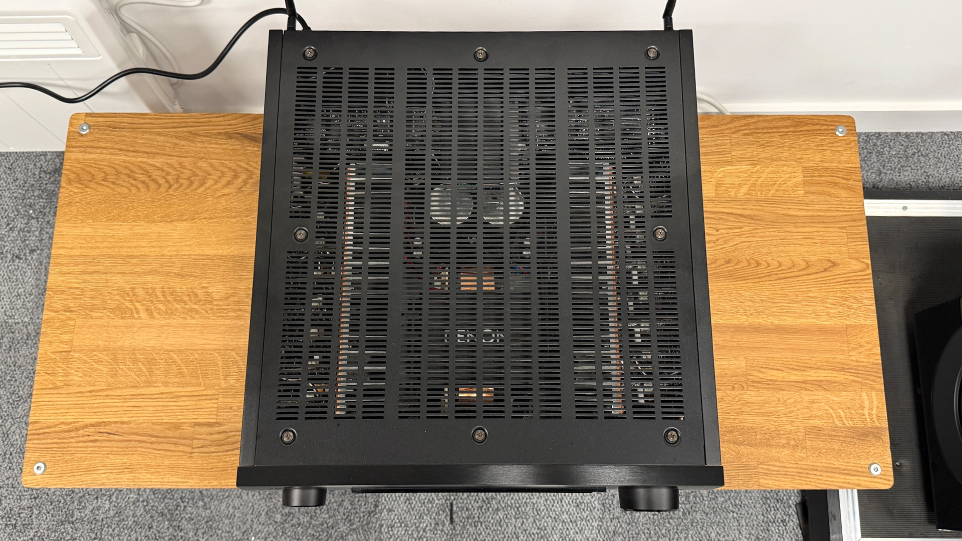 Denon AVC-A1H AV amplifier on wooden AV rack showing top of amp