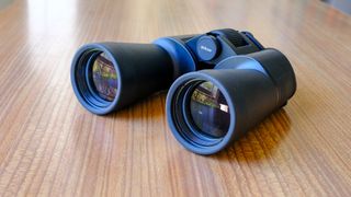 The Nikon Action 16x50 binoculars on a wooden table.