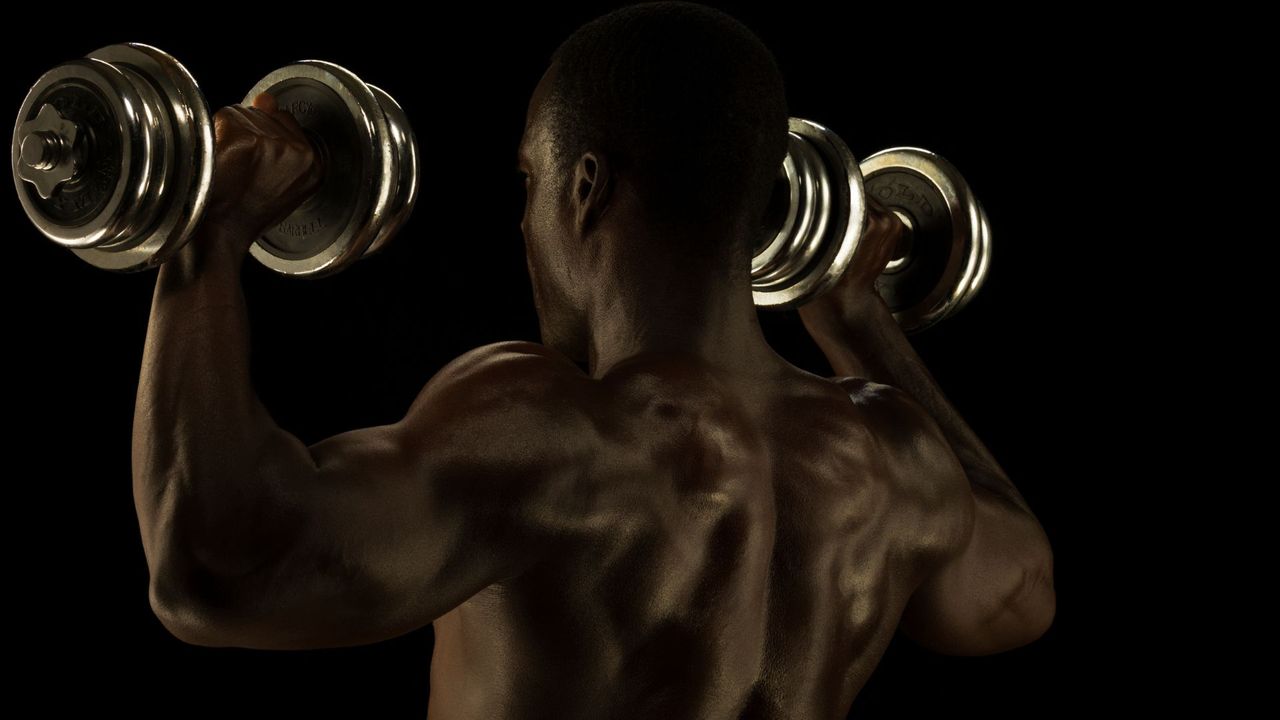 Man performing shoulder press exercise with dumbbells