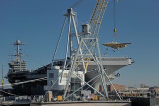 The U.S. Navy's X-47B drone is hoisted aboard the aircraft carrier USS Harry S. Truman in preparation for flight testing at sea.