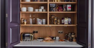 Green kitchen with bi fold pantry concealing a breakfast bar to show a popular kitchen trend 2023