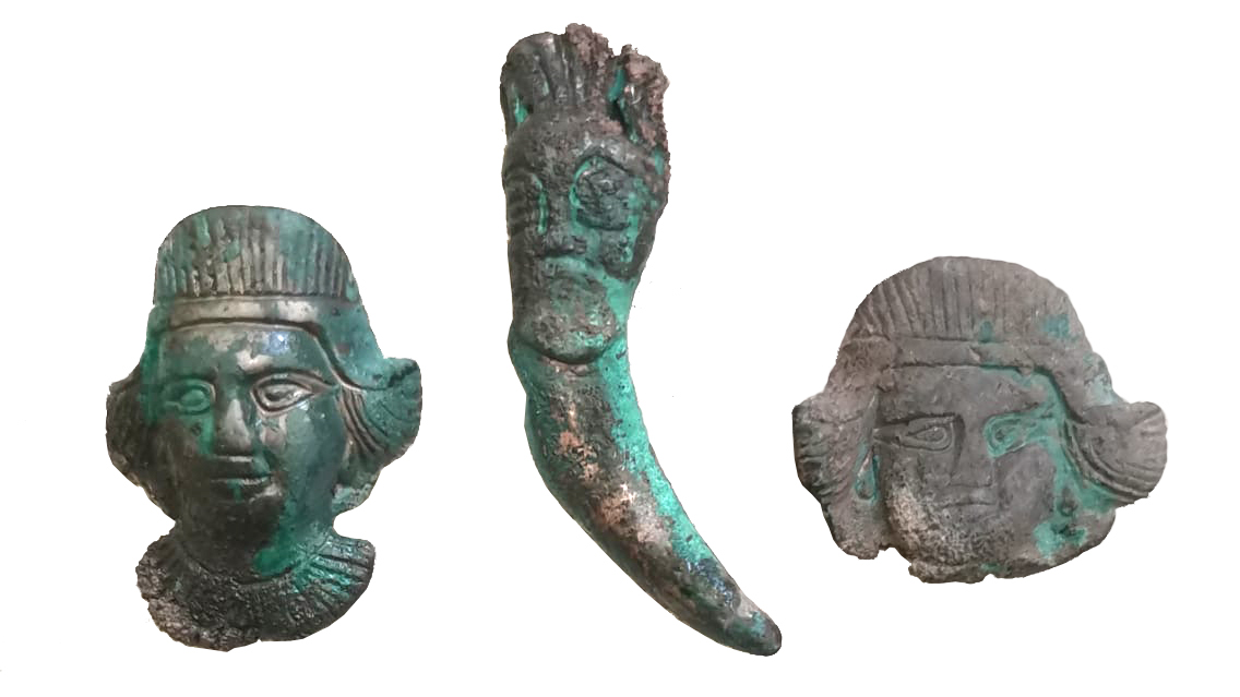 three oxidized bronze horse bridal fittings in the shape of human faces