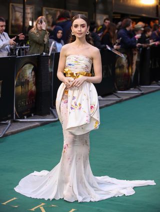 Lily Collins attends the "Tolkien" UK premiere at The Curzon Mayfair on April 29, 2019 in London, England wearing a white floral Giambattista Valli gown.