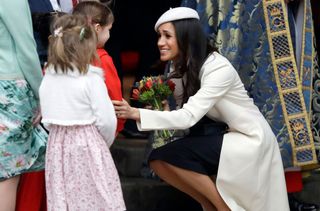 Meghan Markle receives flowers from a child as she leaves after attending the Commonwealth Service at Westminster Abbey