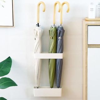 White Wall Mounted Umbrella Holder with three umbrellas stored inside it. 