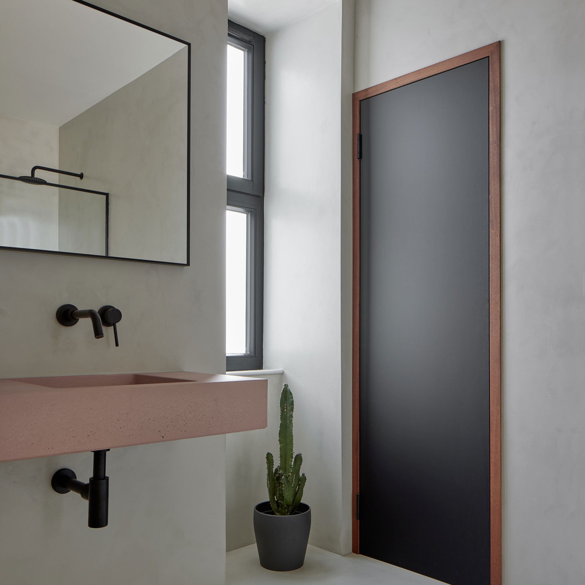 contemporary pink coloured sink with black taps in a cloakroom