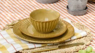 Mustard bowls and plates which are softly fluted on a gingham tablecloth