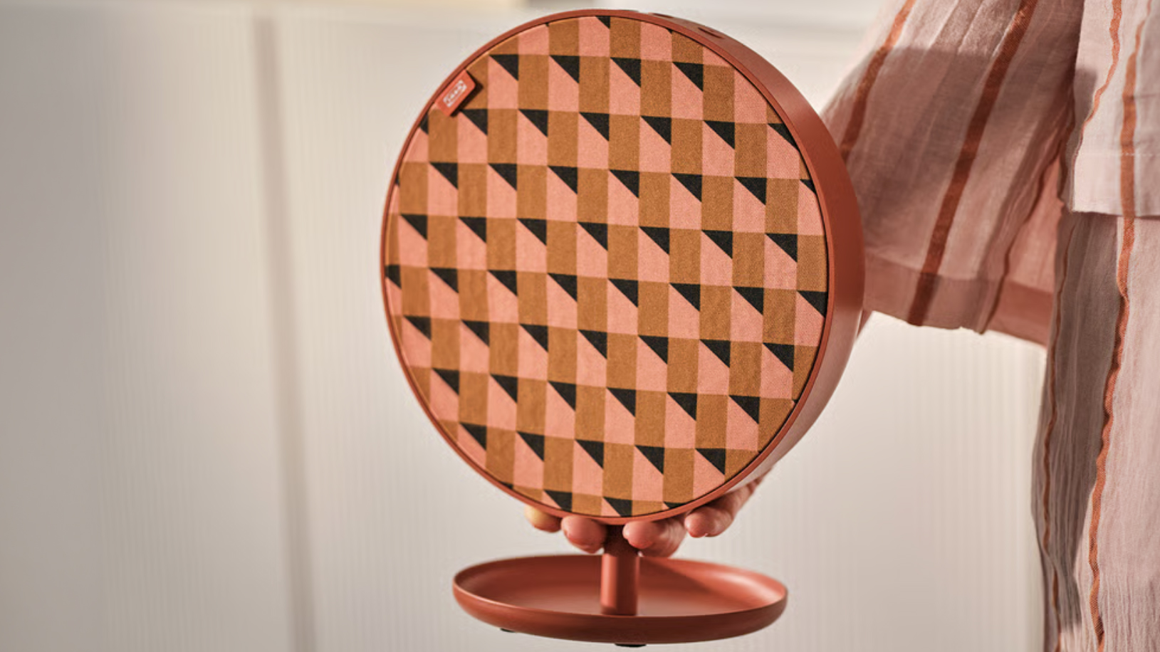Someone holding the IKEA Solskydd speaker in orange