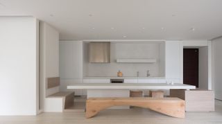 KOA Apartment by Marty Chou Architecture - a large white kitchen table with benches either side.