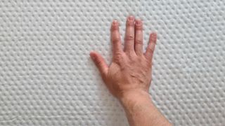 A hand pressing down on the Emma Luxe Cooling Mattress