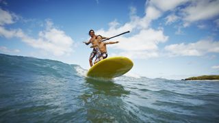 Father and son riding wave on stand up paddleboard