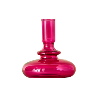 A glass magenta tinted taper candle holder in a modern geometric shape