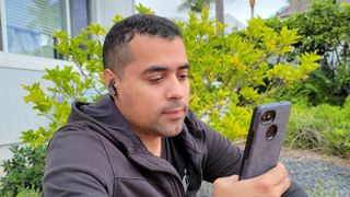 The reviewer wearing the Edifier NeoBuds Pro earbuds while looking at a smartphone