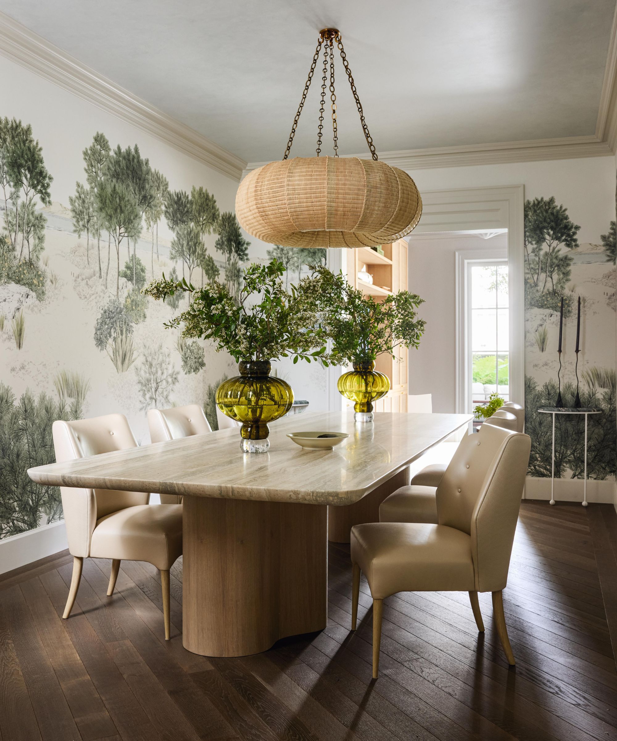 a mural wrapped dining room with a large stone dining table and leather chairs