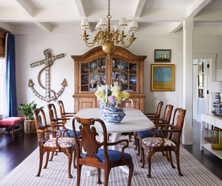 dining room with dark wood chairs pale table and striped rug anchor wall hanging