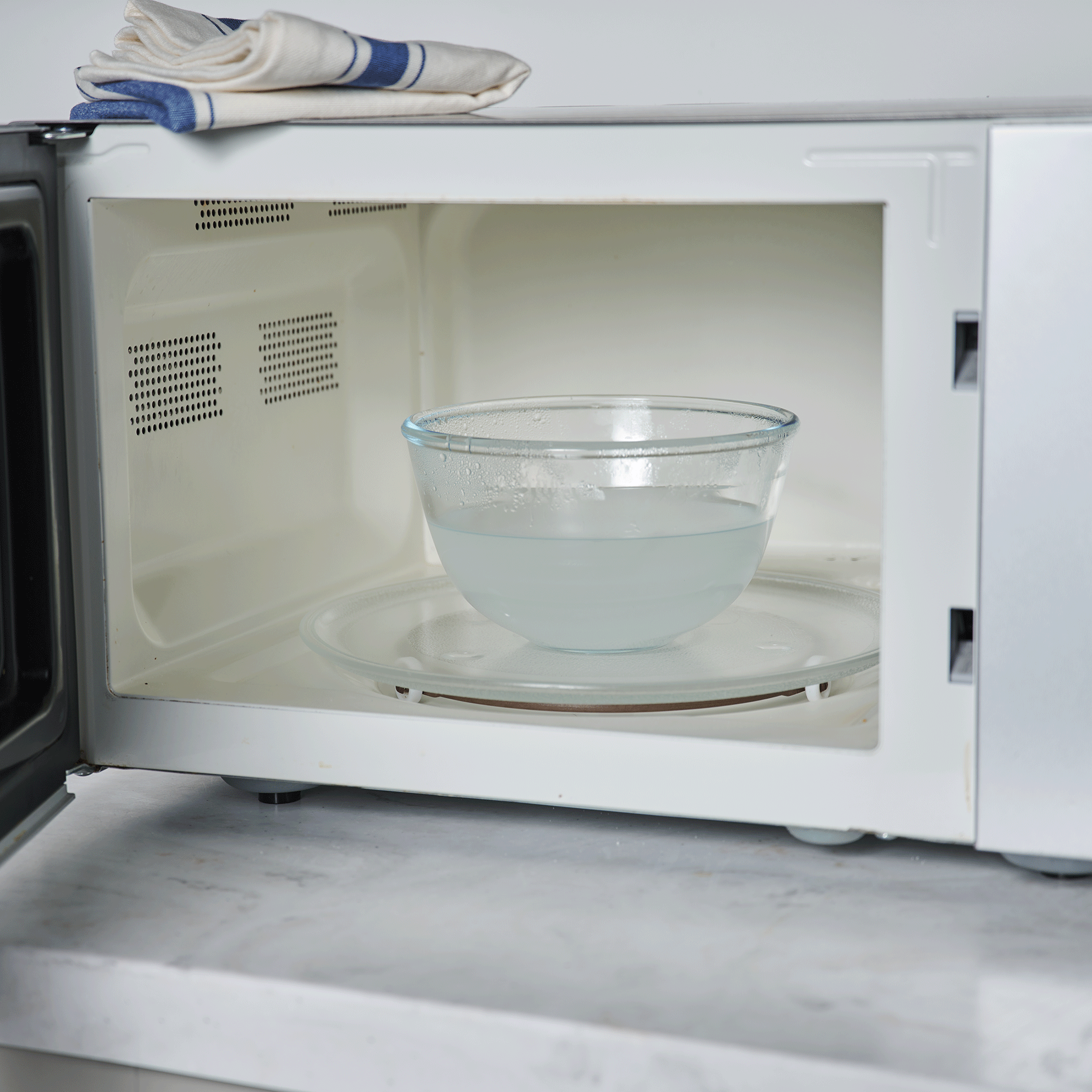 White microwave with bowl of vinegar