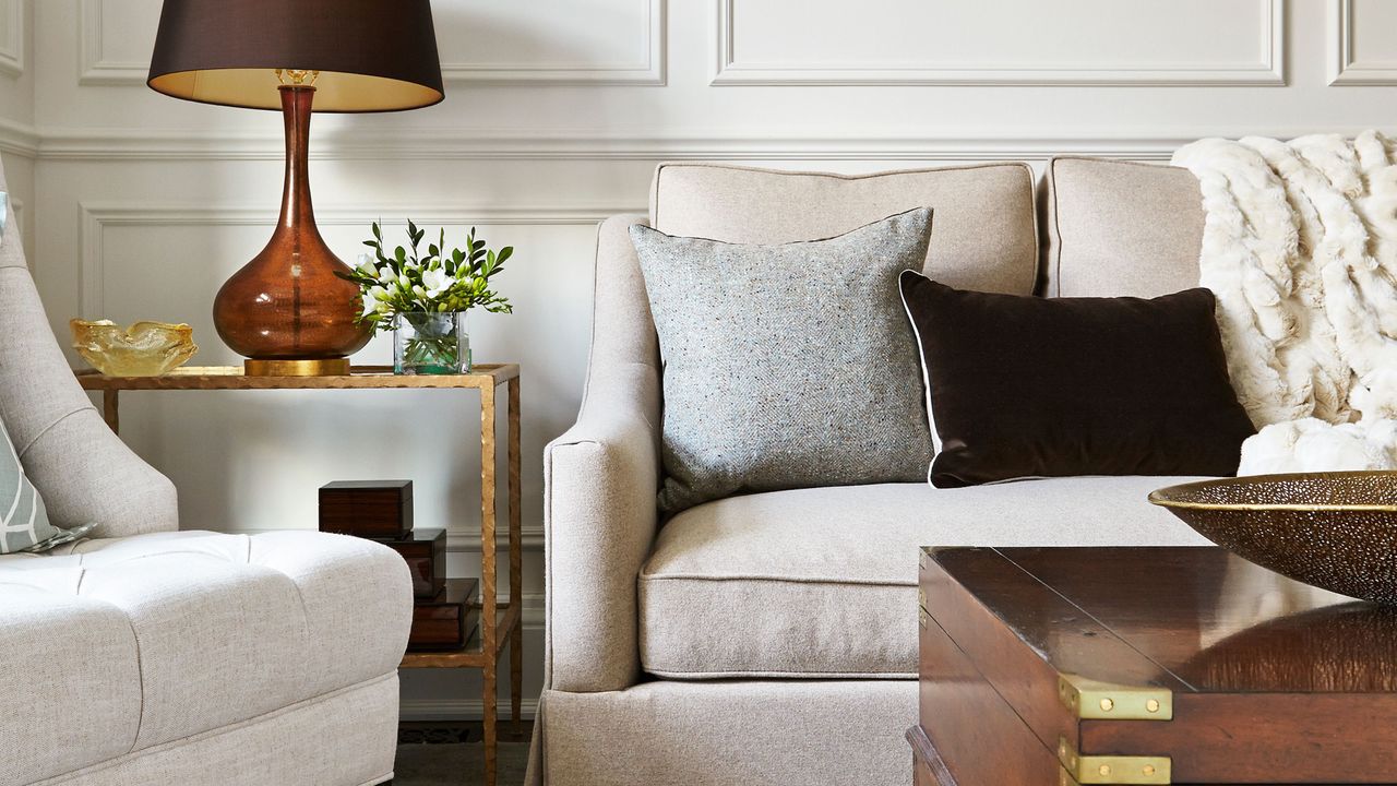 Seating ideas for small living rooms are always useful. Here is a small living room with a white couch and armchair, a wooden coffee table, a brown lamp, and white walls