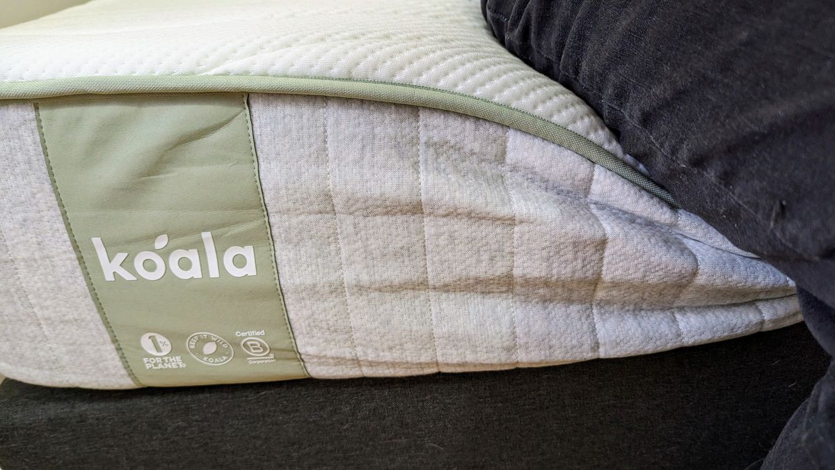 Close up of a person sitting on the end of the Koala SE mattress, showing edge support