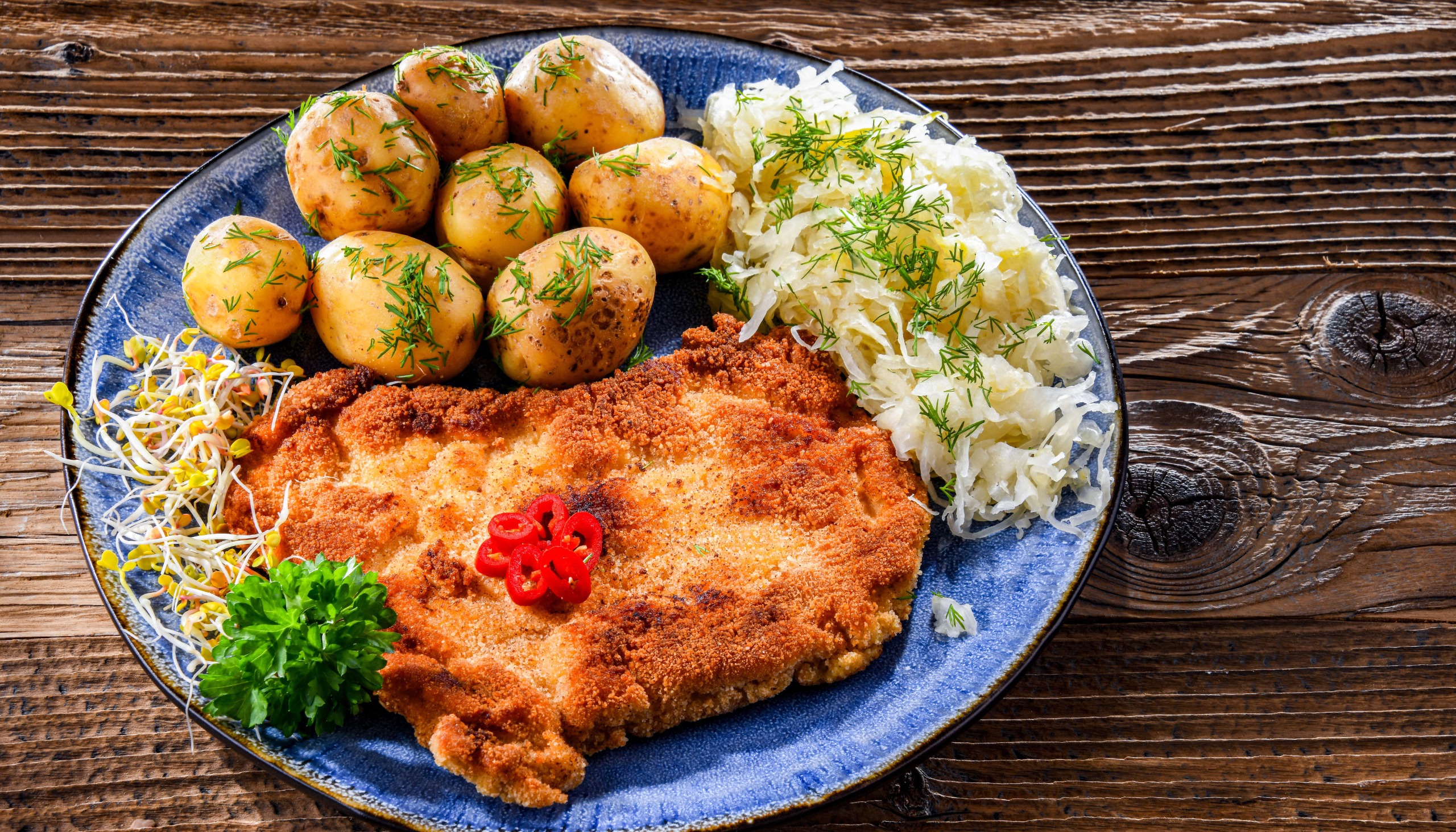 A plate of schnitzel, potatoes and sauerkraut