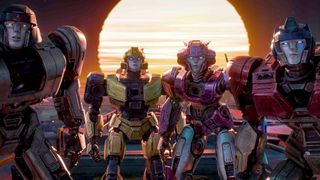 A picture of four transformers looking back at the camera with a low setting sun in the background