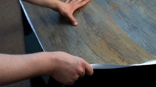 Hands laying down vinyl wood-effect surface