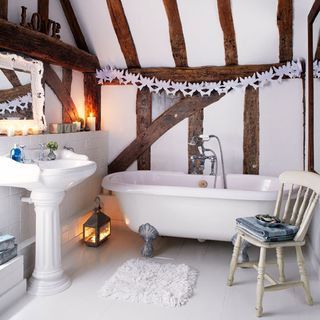 bathroom with white wall and wooden beam and bathtub and washbasin and chair