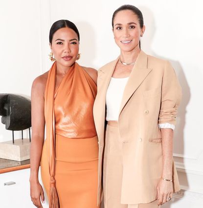 Meghan Markle in a beige suit posing with Emma Grede