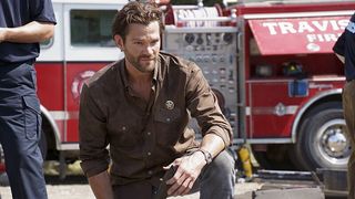 Jared Padalecki as Cordell Walker kneeling in front of a fire truck in Walker