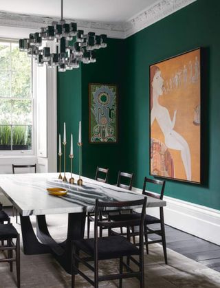Dining room with green walls and statement artwork