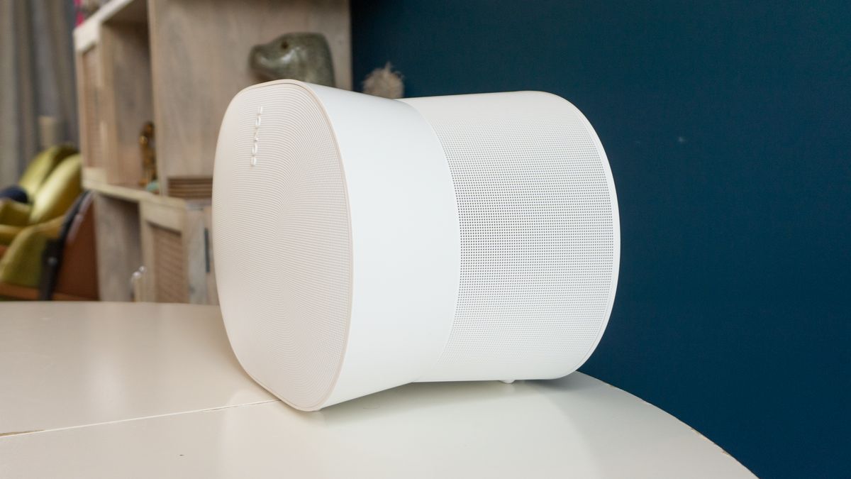 The Sonos Era 300 on white table, viewed from the side. We can see its 'bow'-like shape, where the front and rear are taller than the middle.