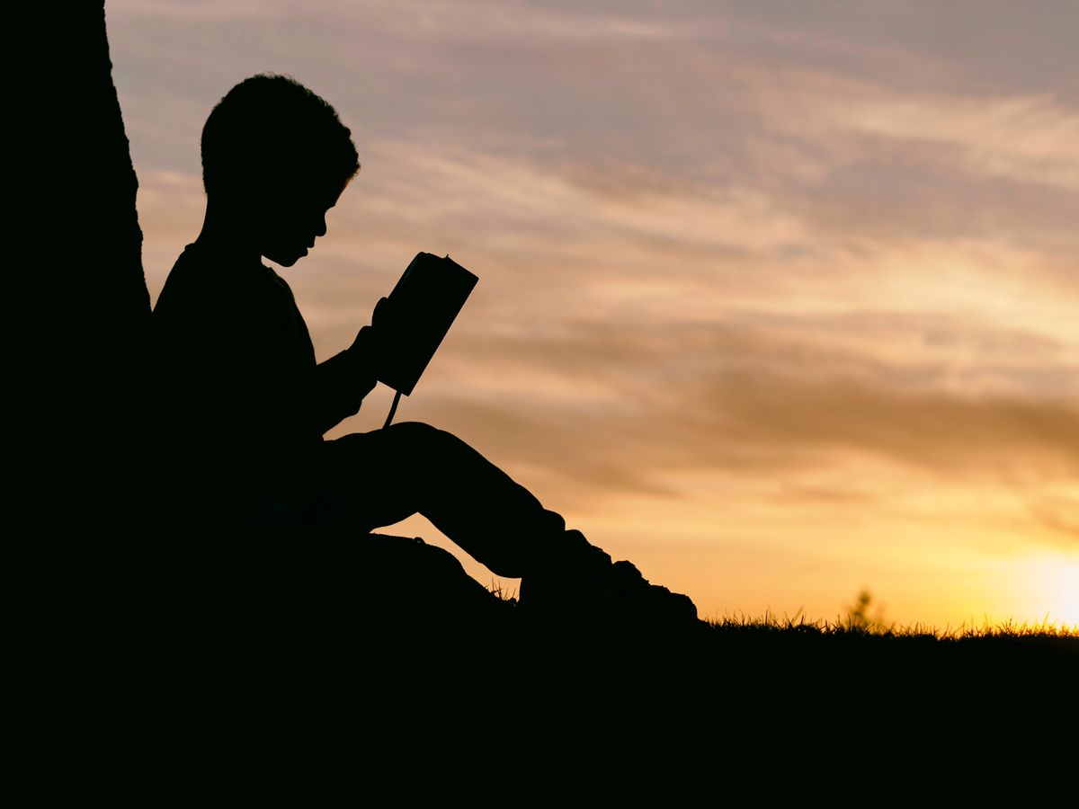 Silhouette of boy reading traditional book