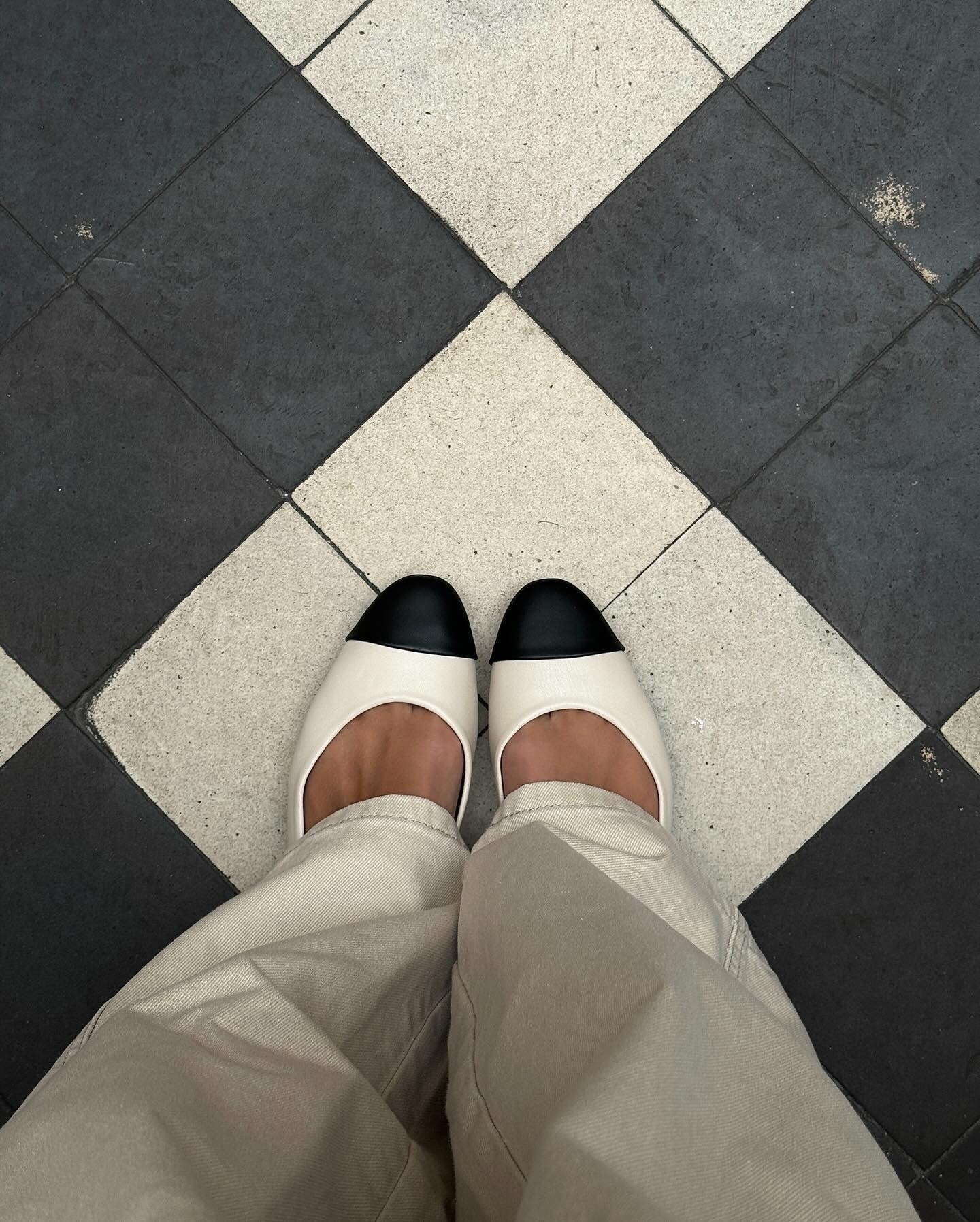 a selfie of a woman's feet wearing white jeans and white flat shoes