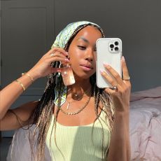 @amaka.hamelijnck holding a bottle of fake tan while taking a mirror selfie with her iPhone