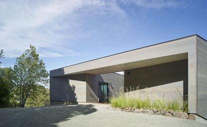 The grey cedar wood cladding helps Schwartz and Architecture's Box on the Rock house to blend into its rocky landscape