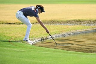 Golfer picks ball out from water