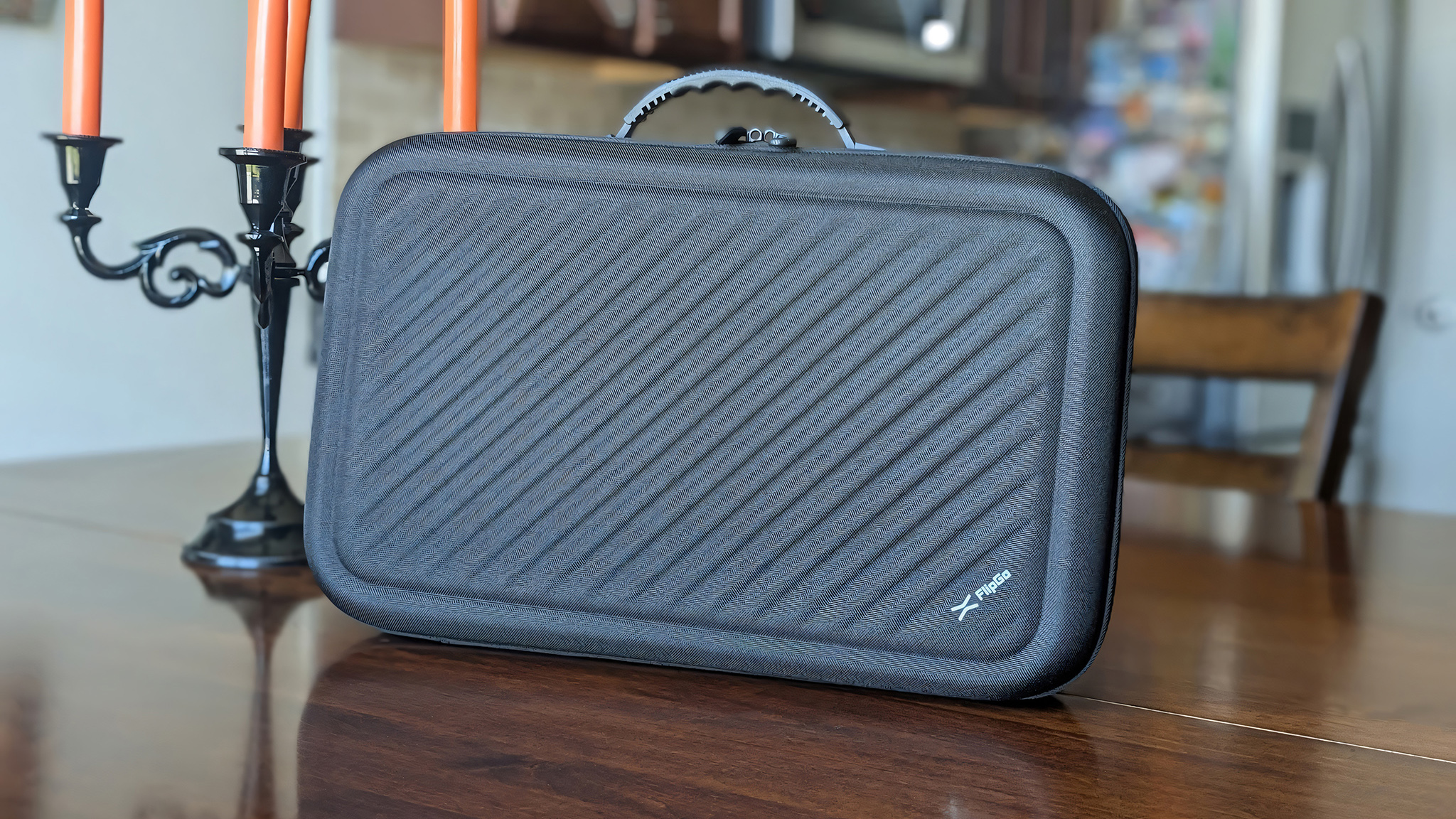 The JSAUX FlipGo Horizon Pro's black hard shell carrying case next to a candelabra.