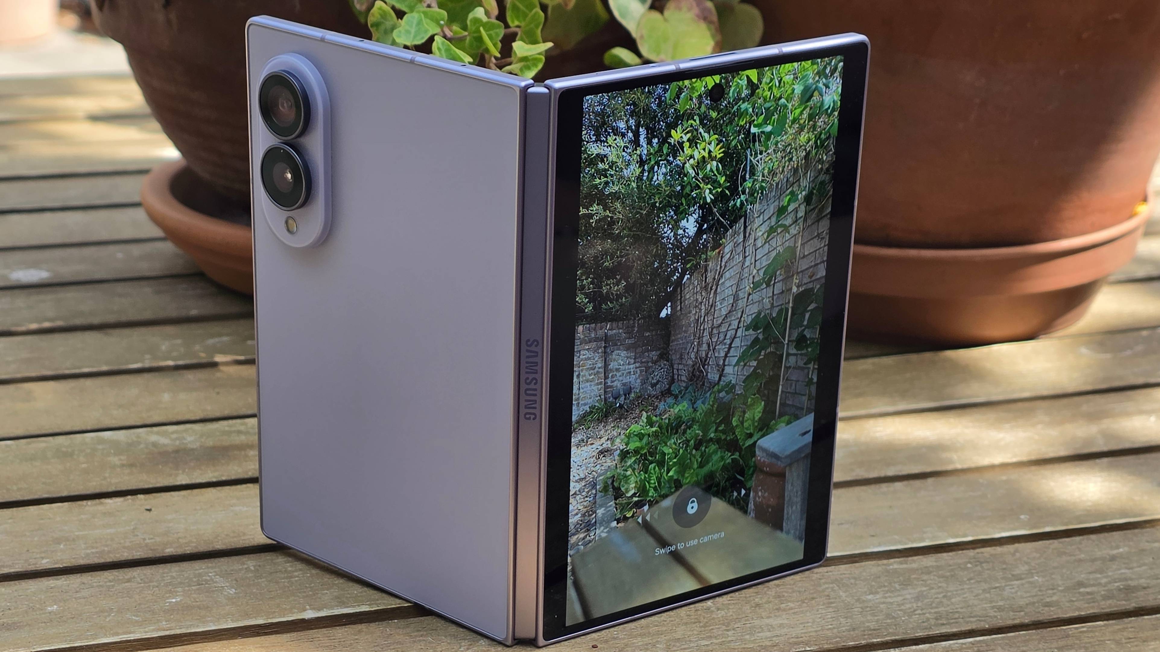 The Samsung Galaxy Z Fold 8 on a wooden table, slightly ajar to show the camera viewfinder.