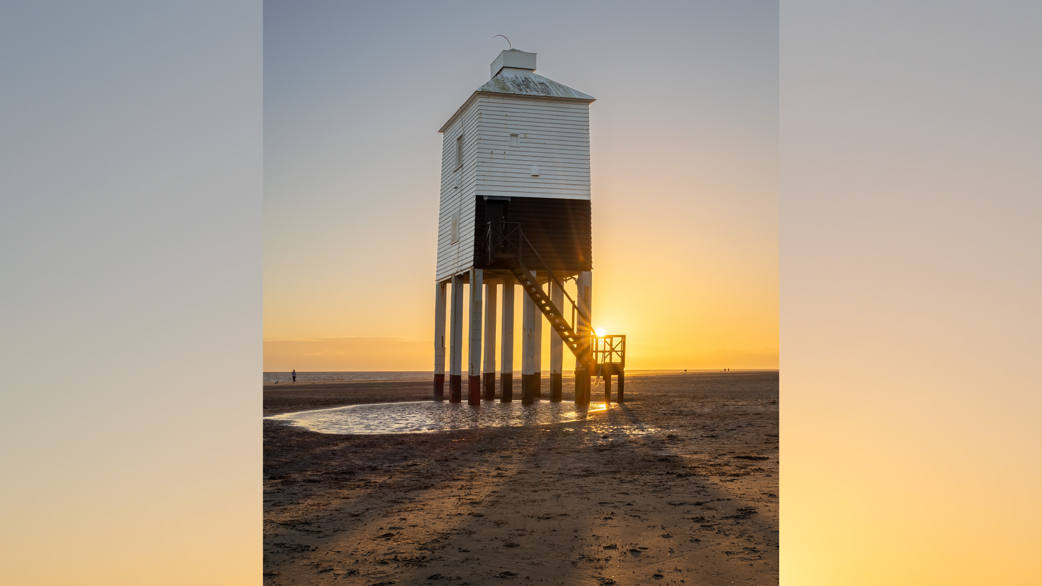 lighthouse on a beach at sunset