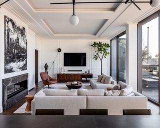 white living room with white sofas, monochrome artwork, fireplace, patterned rug, wooden console and TV
