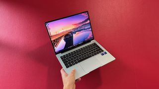 A hand holds aloft the opened Huawei MateBook 14 for all to see. 