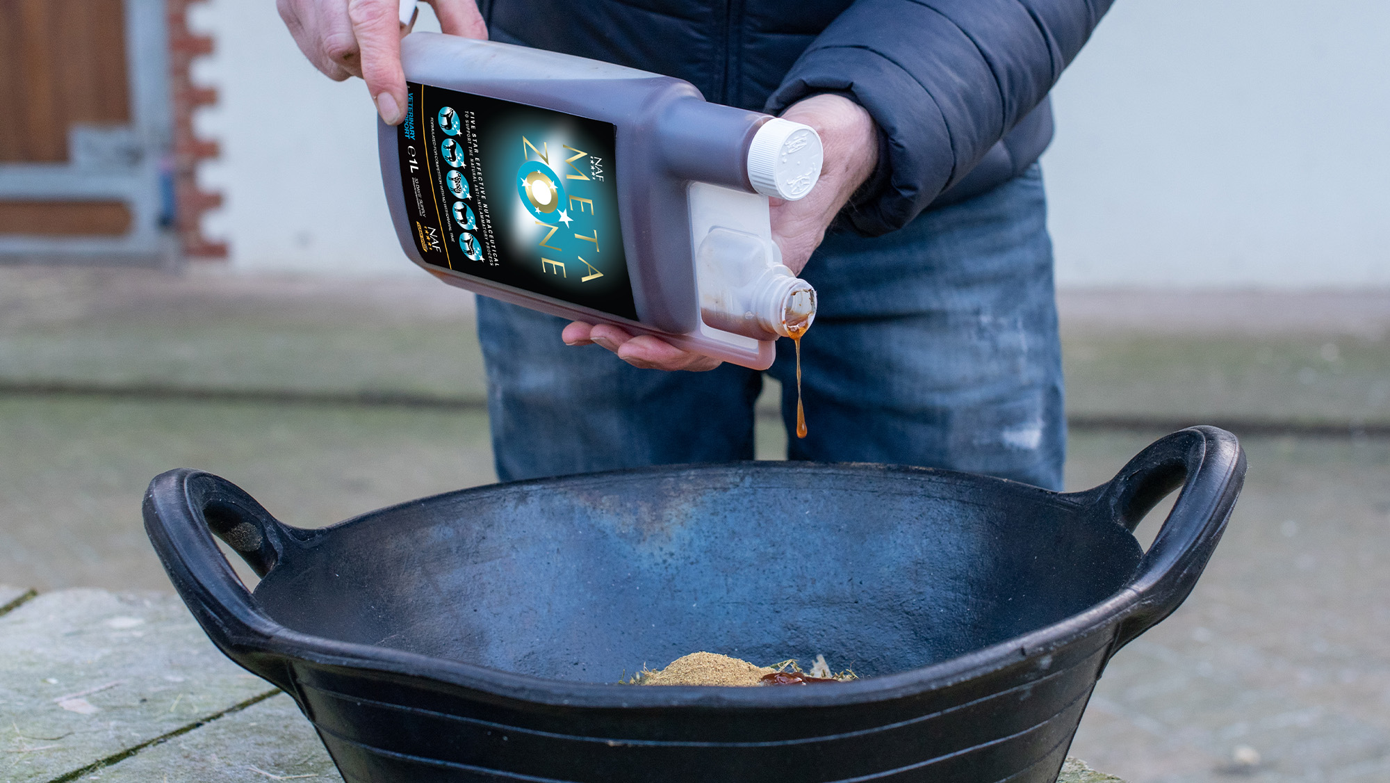 Close up of person pouring liquid supplement into horse feed