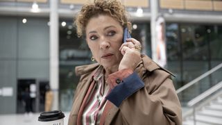 Alex Kingston in a beige coat on the phone as Sheila in Douglas is Cancelled